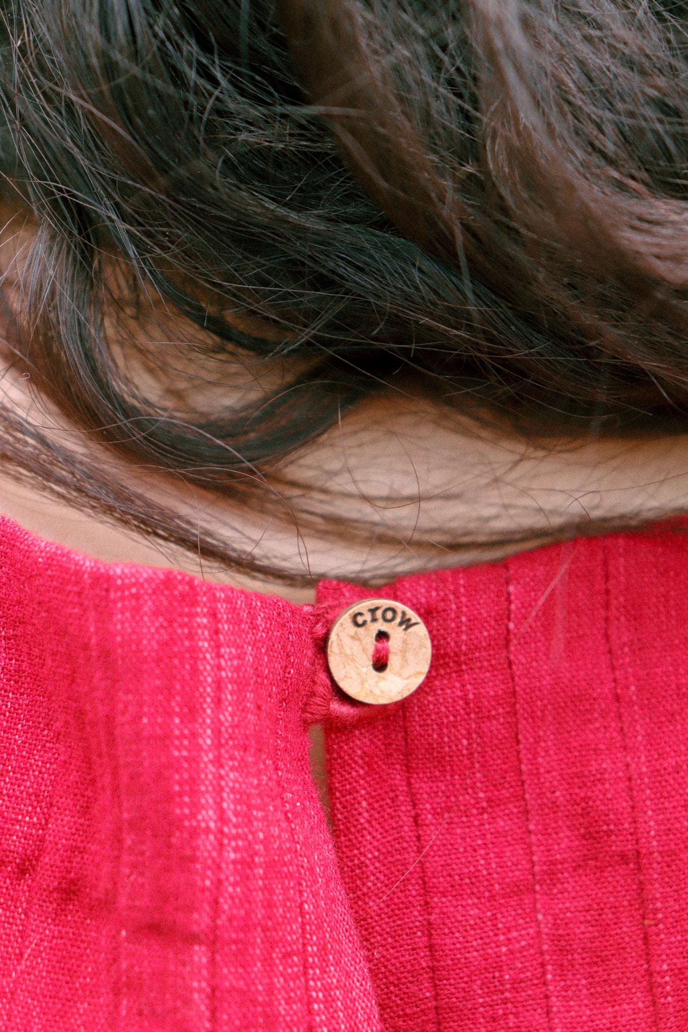 Close-up of a red garment with a button featuring 'COTW' branding.